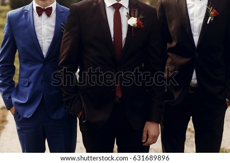 stylish groom with groomsmen in suits with boutonniere posing, getting ready in morning for wedding ceremony Royalty-Free Stock Photo #631689896