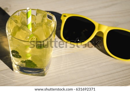 sunglasses, yellow cocktail with mint and ice/cocktail with mint and sunglasses