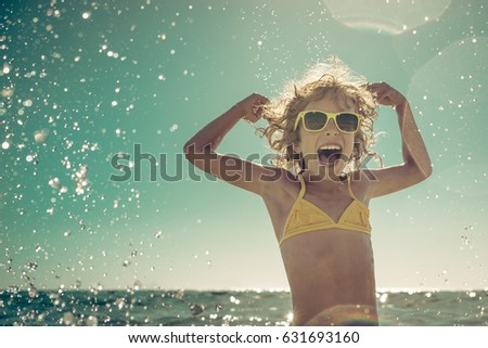 Happy child playing in the sea. Kid having fun at the beach. Summer vacation and active lifestyle concept