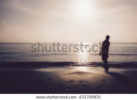 Mother absorbing your sun walking sand beach with sunset background and reflex in ocean.Concept for mother's day and silhouette style