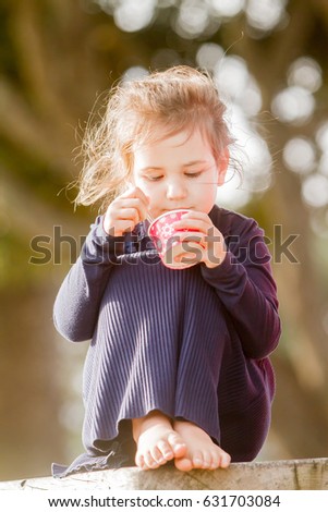 outdoor portrait of young child girl eating ice cream on natural background
