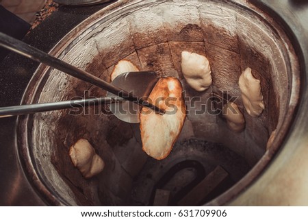 Baker making turkish pita bread in tandoor (clay oven). Baking process