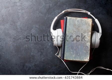 Audio book concept. Headphones and old books over stone table. Top view with space for your text