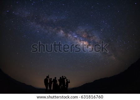 Landscape with milky way, Night sky with stars and silhouette of happy people standing on moutain, Long exposure photograph, with grain.