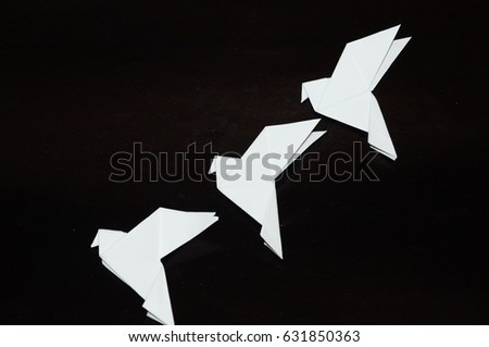 Origami pigeons on a black background. A white dove in flight is isolated on a black background. A paper dove is isolated on a black background.
