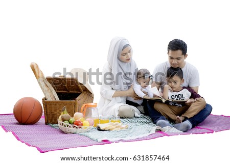 Picture of Muslim family enjoying a picnic while reading a book and sitting in the studio