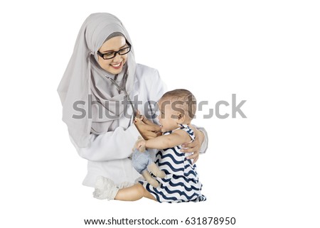 Image of Muslim female doctor checking a baby with a stethoscope in the studio, isolated on white background