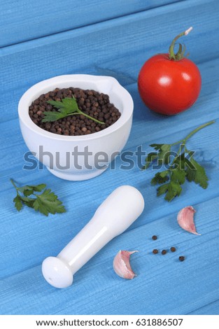 Black pepper in white glass mortar and fresh vegetables on blue boards, seasoning for cooking