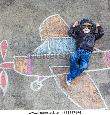 Creative leisure for children: Funny little child of four years having fun with airplane picture drawing with chalk.