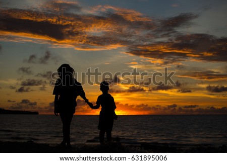 Mom and son at sunset by the ocean. Happiness, family, childhood.