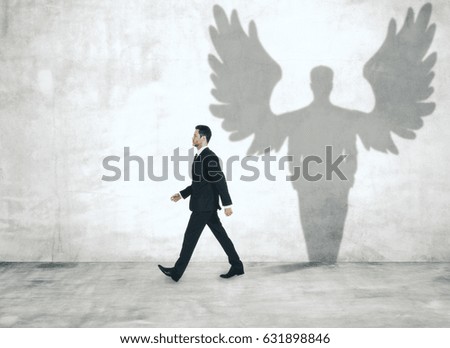 Walking man with angel shadow in concrete interior