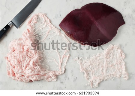 Raw liver and animal fat net on a marble table. Step by step cooking