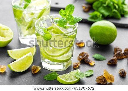 Summer mint lime refreshing cocktail mojito with rum and ice in glass on black background Royalty-Free Stock Photo #631907672