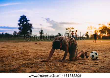 Kids are playing soccer football for exercise under the sunlight. Picture for concept of sad, regret,lose and defeated.