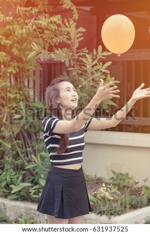 asia young girl hold and play balloon. with retro filter. at outdoor background.