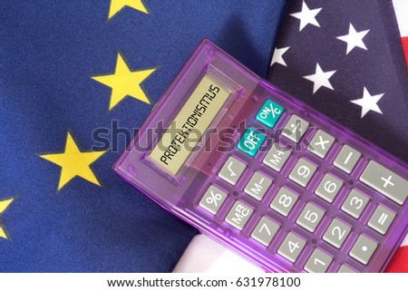 Flags of the EU and the USA and a pocket calculator with the German word for protectionism