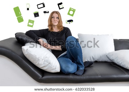 Closer view of grinning long haired young woman sitting on a black and white couch with black and white pillows. Woman is looking upwards on the illustration of a home appliance in the background. 