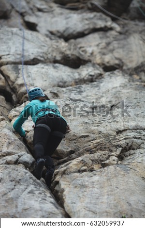 A girl climber climbs the rock wall. Competitions in rock climbing.