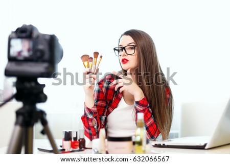 A young girl blogger writes a new edition.Beauty-blog.Girl beauty blogger in front of a camera talks about the new makeup..a Girl with a laptop sitting at the table.Cosmetics on the table