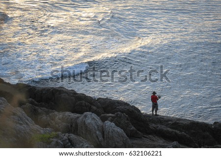Men fishing along the banks of the sea in the evening.