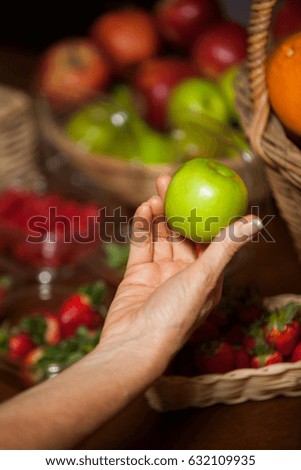 Hand of female staff holding a apple in supermarket