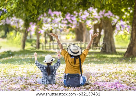 Asian mother and daughter taking photo in the park together with pink flower on floor,Concept of family travel. Royalty-Free Stock Photo #632139431