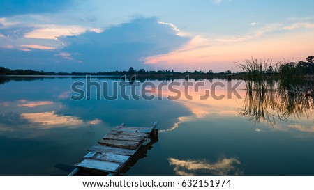 wooden bridge at the lake on the background of colorful sky sunset