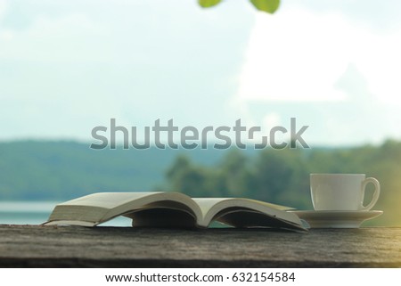 Relaxing moments , Cup of coffee and a book on wooden table in nature background, color of vintage tone and soft focus.