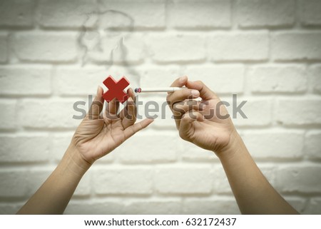 Hand holding cigarette with black smoke and woman hand holding red cross, No smoke concept.