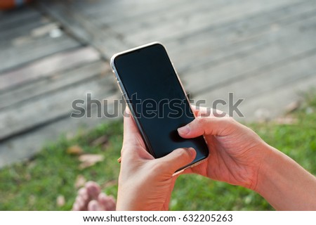 Woman using smart phone with thumb on wood and grass background