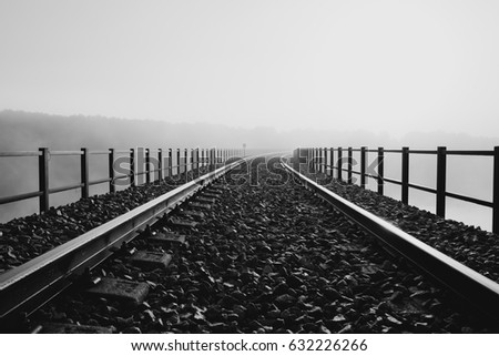 Railway over a bridge disappearing into the morning mist.
