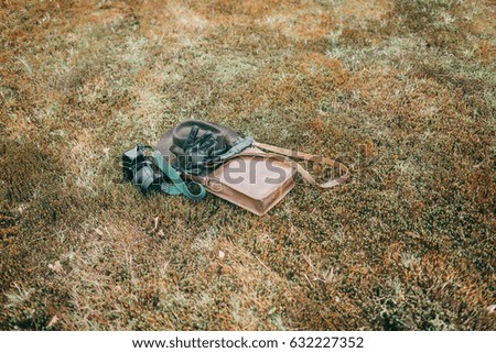 Leather bag with gloves and camera lying in meadow. High angle view.