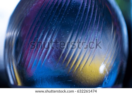 A plastic bottle filled with clean, clear water with bubbles, is highlighted by a multicolored light. Surface with a pattern in the form of diagonal lines.