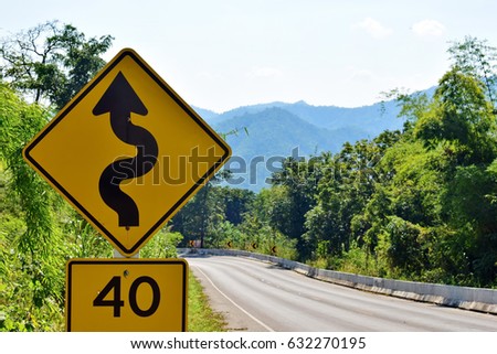 Curved warning signs and speed limits on the road. Selective focus.