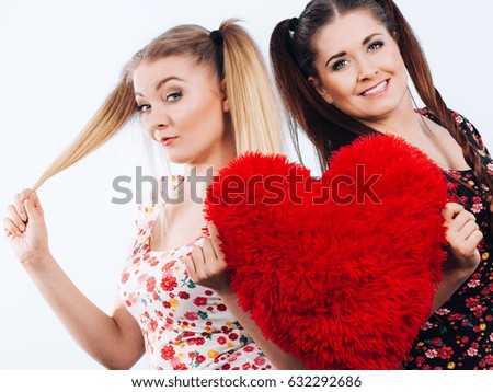 Happy two teenager women holding heart shaped pillow. Valentines day gift ideas, teenage love concept.