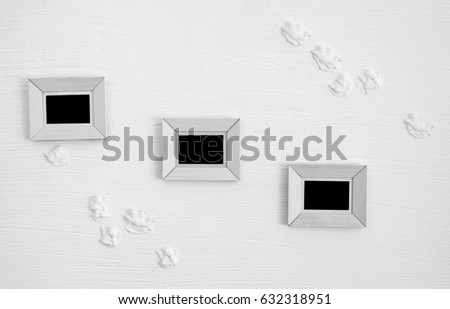 Three white wooden photo frames on the decorated wall