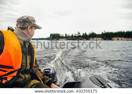 Tourist on a Fishing Trip in a Life Jacket Driving and Maneuvering on Inflatable Boat Royalty-Free Stock Photo #632350175
