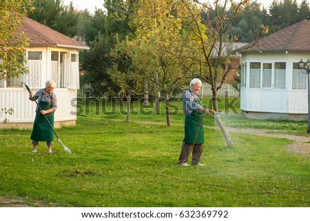 Man with garden hose. Couple of seniors outdoors. Jobs in horticulture.