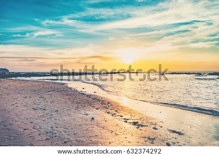 Coast of the sea at colorful sunset, Nang Thong Beach, Andaman Sea, Khao Lak, Thailand. Beach sunset is a golden sunset sky with a wave rolling to shore as the sun sets over the ocean horizon.