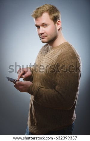 angry young man talking on cell phone isolated on gray background