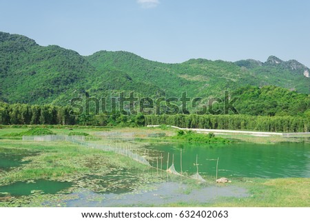 Beautiful landscape of Van Long Nature Reserve - the set of Kong Skull Island movie. Ecology system with natural pond and row of mountain in background. The rural wetland of Ninh Binh, Vietnam.