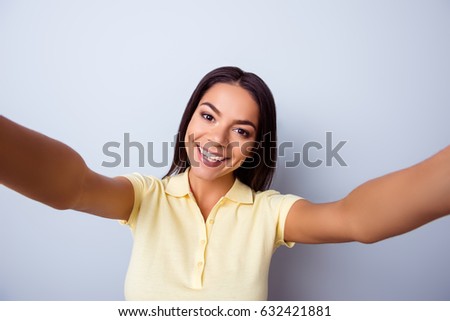 Close up portrait of cute excited latin girl making selfie with camera of her pda. She is in casual closes, has a beaming smile