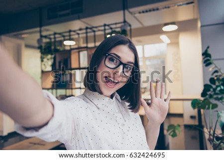 Pretty young smiling girl in glasses taking a selfie