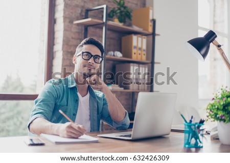 Portrait of minded young student sitting at the table in front of computer and writing a composition for essay contest in high-school Royalty-Free Stock Photo #632426309