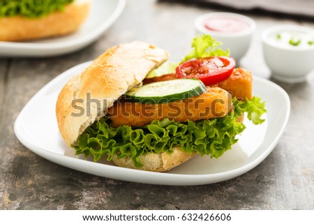 Hearty fish fillet sandwich with salad and veggies.