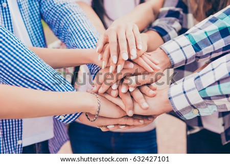 close-up photo of young friends putting their hands on top of each other. They achievement harmony in team