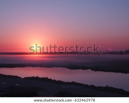 The peaceful crack of dawn with pink sun rising up above the horizon while the land is covering with white mist in Freeport, Bahamas Royalty-Free Stock Photo #632462978