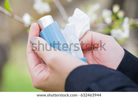Close up picture of an asthma inhaler in a woman's hands outdoor during springtime