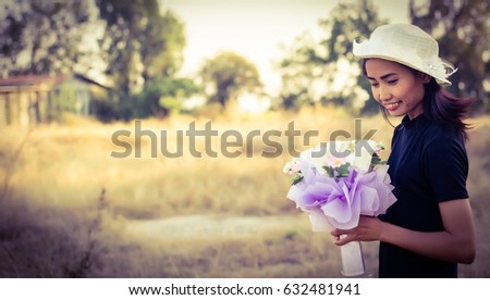 The woman holds flowers among the beautiful pastures.
