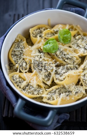 Close-up of conchiglioni baked with cottage cheese and spinach, selective focus, vertical shot
